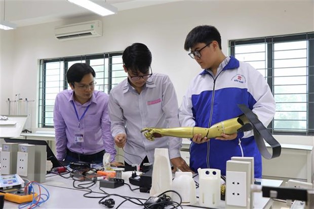 Thầy giáo Ngô Văn Tiến và 2 em Linh, An phân tích, nghiên cứu sản phẩm Cánh tay robot cho người khuyết tật liệt cơ tay toàn phần.